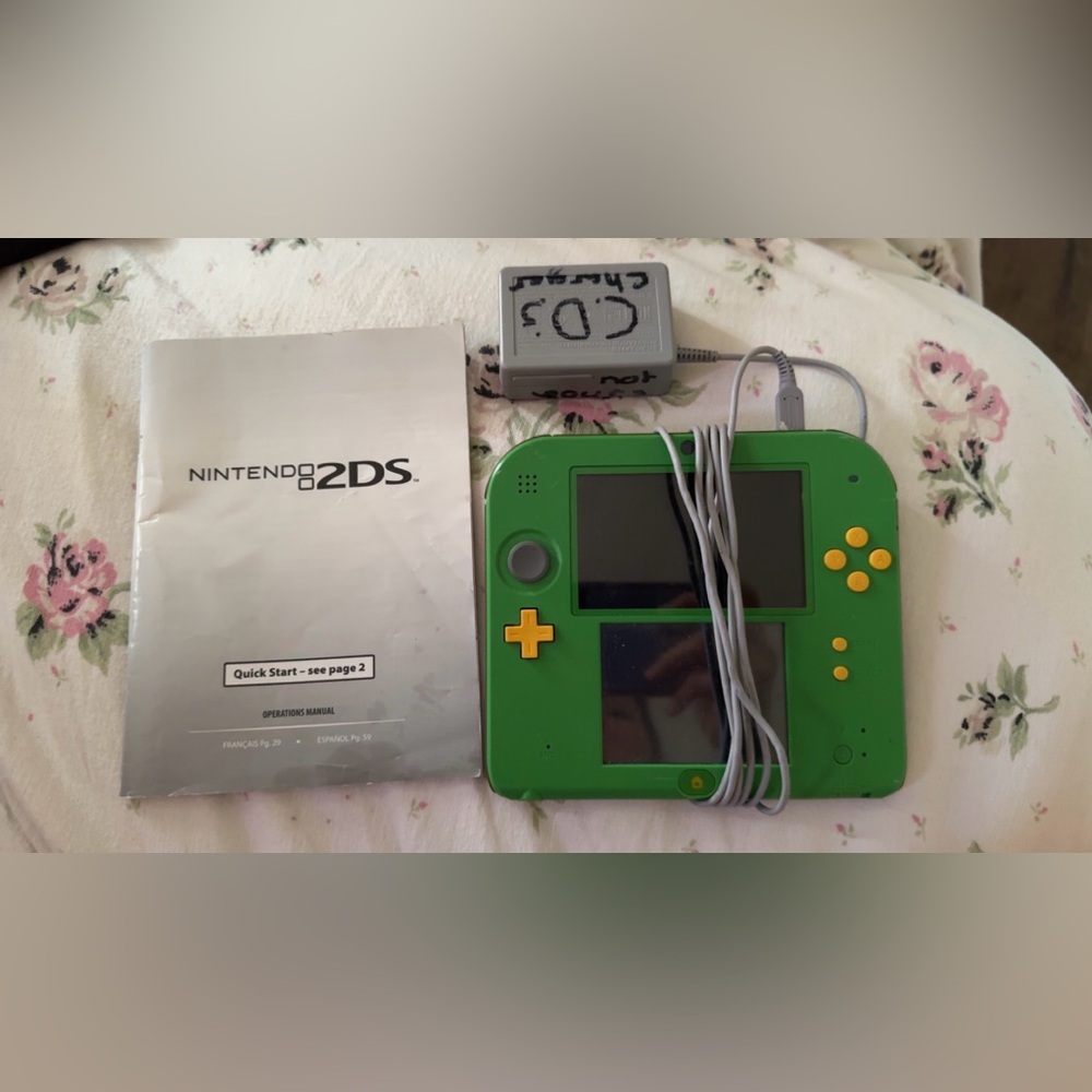 Green Nintendo 2DS with charging cord and pamphlet